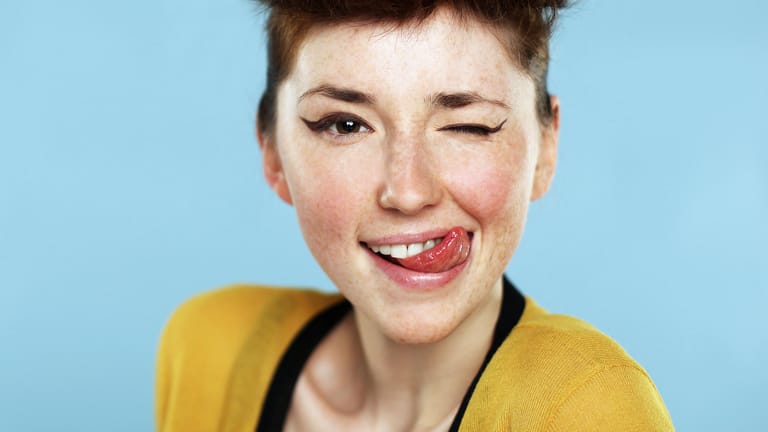 Eine Frau mit Sommersprossen streckt die Zunge raus
