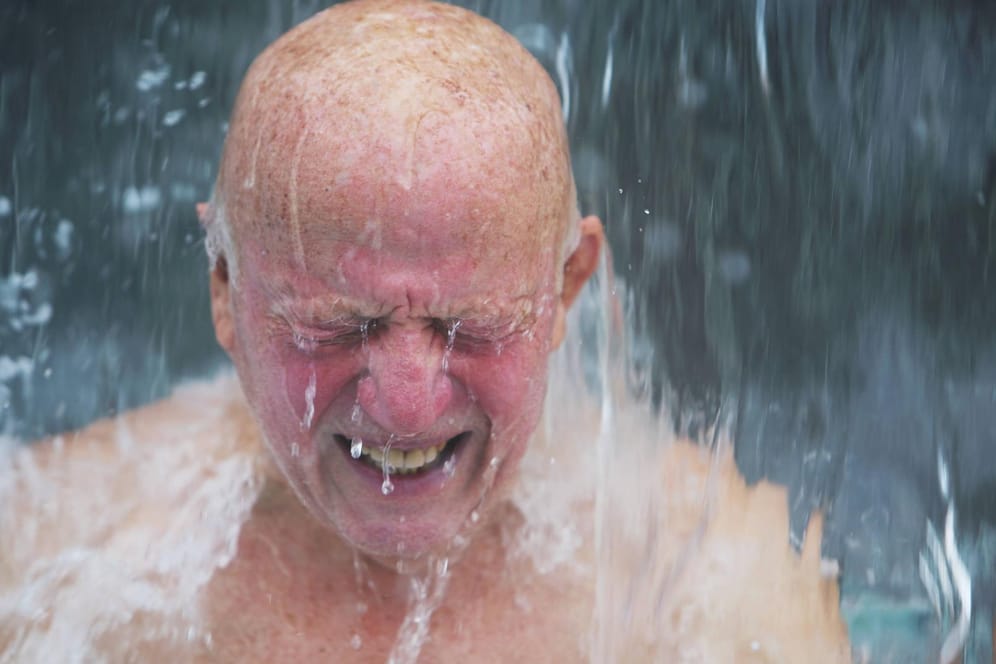 Mann verzerrt sein Gesicht unter der Dusche