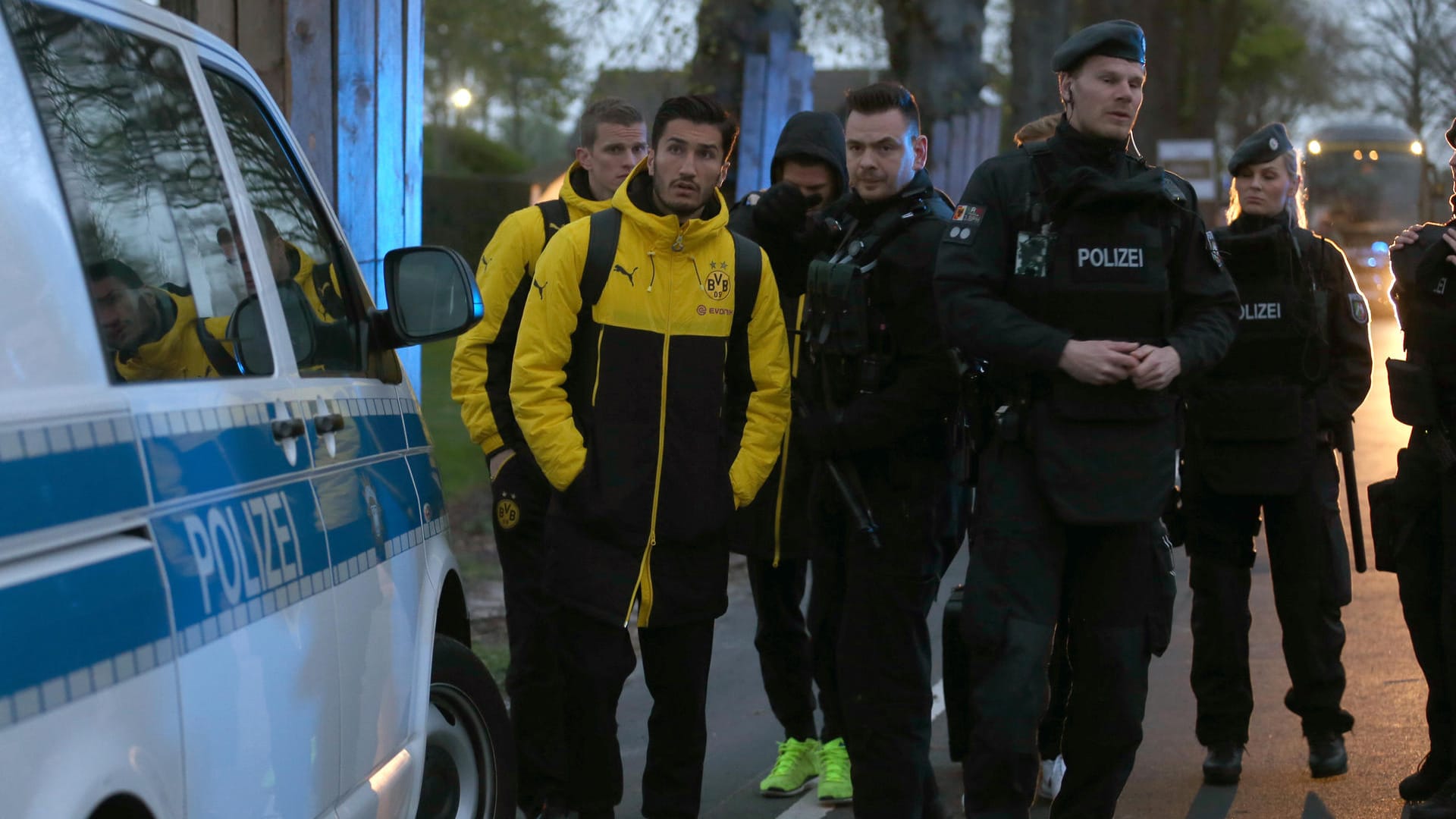 Die BVB-Stars Sven Bender und Nuri Sahin (v.l.) haben sich in Sicherheit gebracht und werden von Polizisten beschützt.