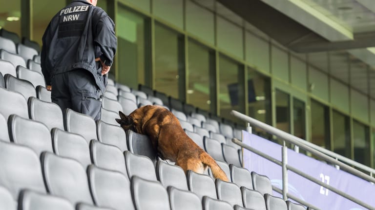 Polizeibeamter und Sprengstoff-Spürhund suchen das Dortmunder Stadion ab.