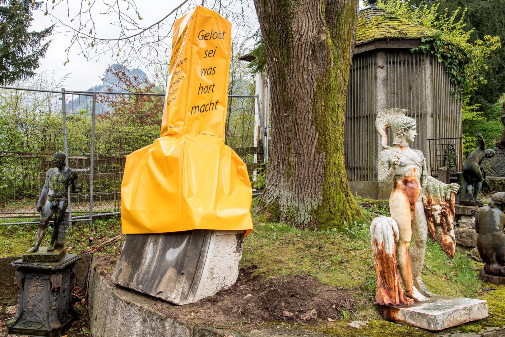Steinerner Phallus mit gelber Hülle