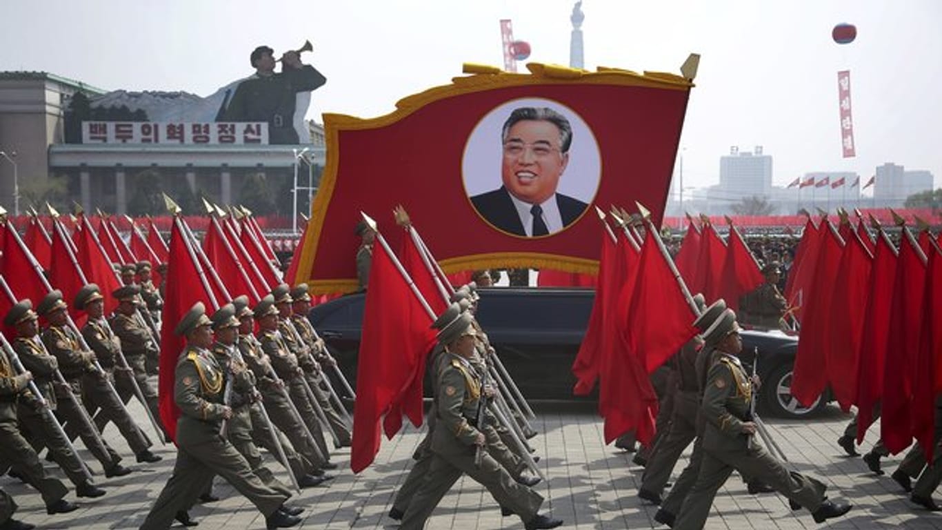 Nordkoreanische Soldaten tragen Flaggen und ein Foto von Kim Il Sung bei der Militärparade in Pjöngjang.