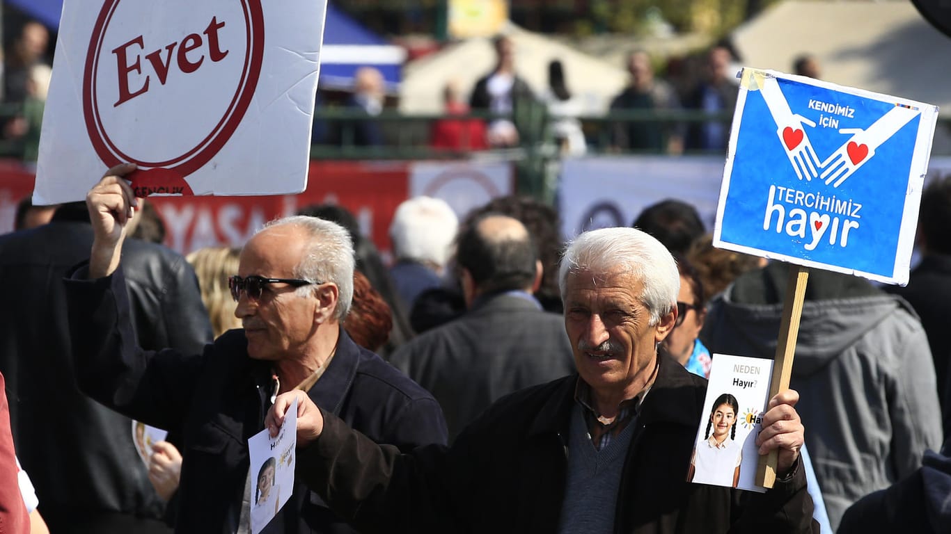 Ein Mann hält ein Schild mit der Aufschrift "Nein" ("Hayir") und ein Mann hält ein Schild mit der Aufschrift "Ja" ("Evet") zum Referendum.