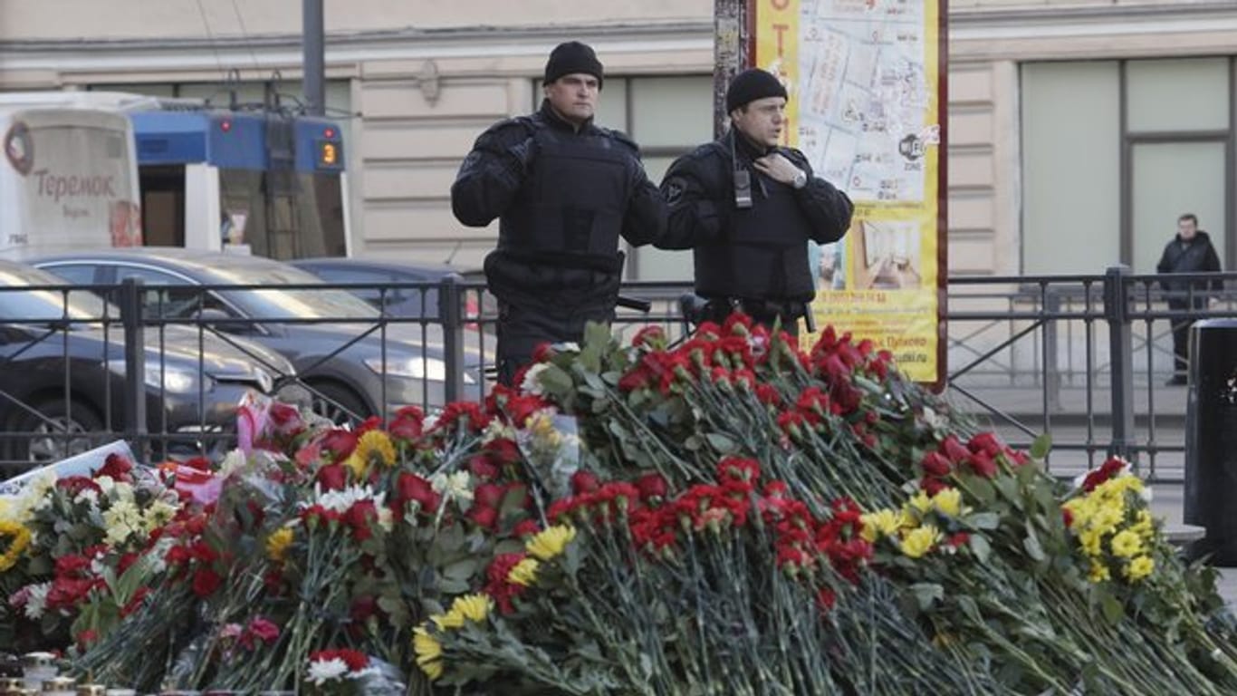 Polizisten vor einer mit Blumen geschmückten Gedenkstätte an der U-Bahn-Station "Technologicheskiy Institute" in St.