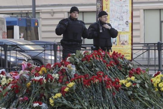 Polizisten vor einer mit Blumen geschmückten Gedenkstätte an der U-Bahn-Station "Technologicheskiy Institute" in St.