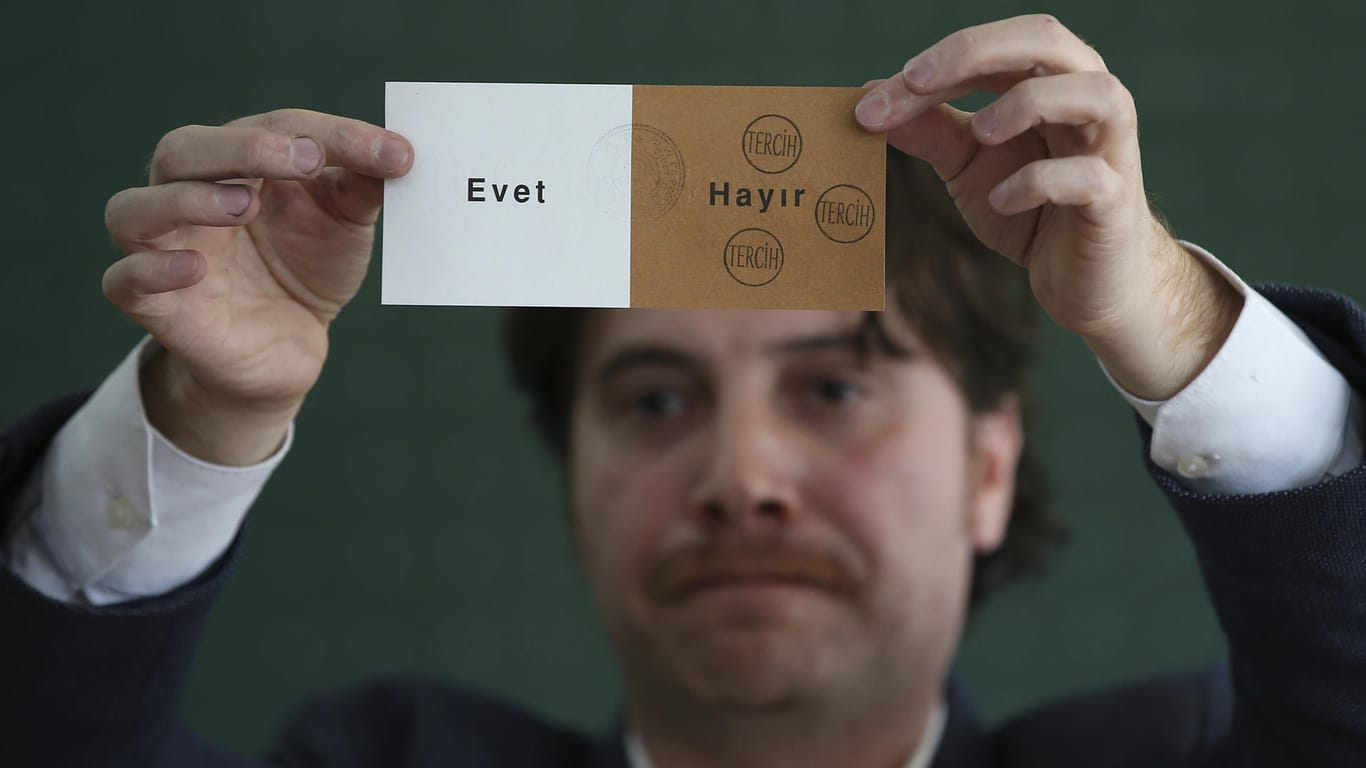 Ein Mitglied eines Wahlkomitees hält in einem geschlossenen Wahllokal bei der Auszählung einen abgestempelten Stimmzettel hoch.