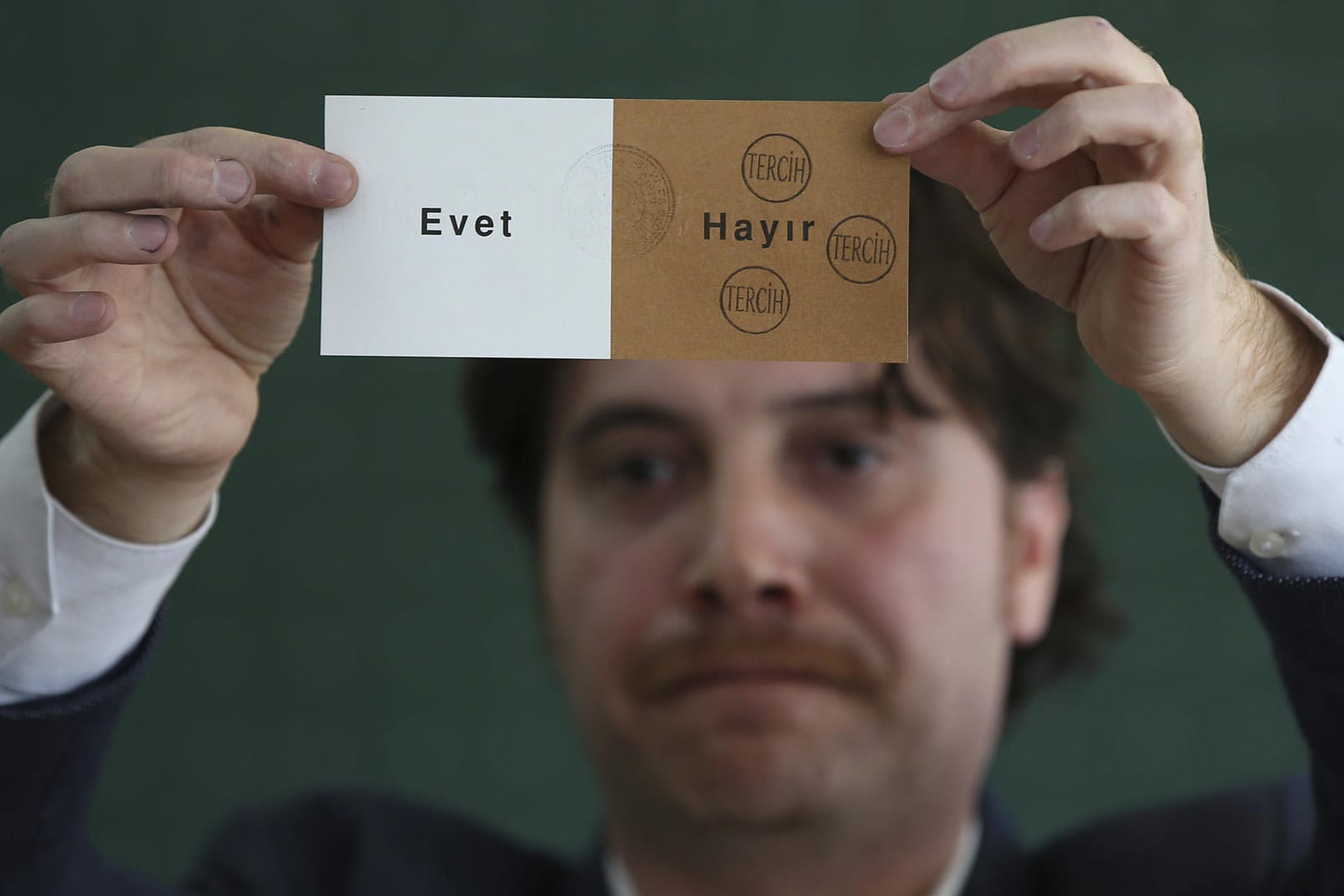 Ein Mitglied eines Wahlkomitees hält in einem geschlossenen Wahllokal bei der Auszählung einen abgestempelten Stimmzettel hoch.