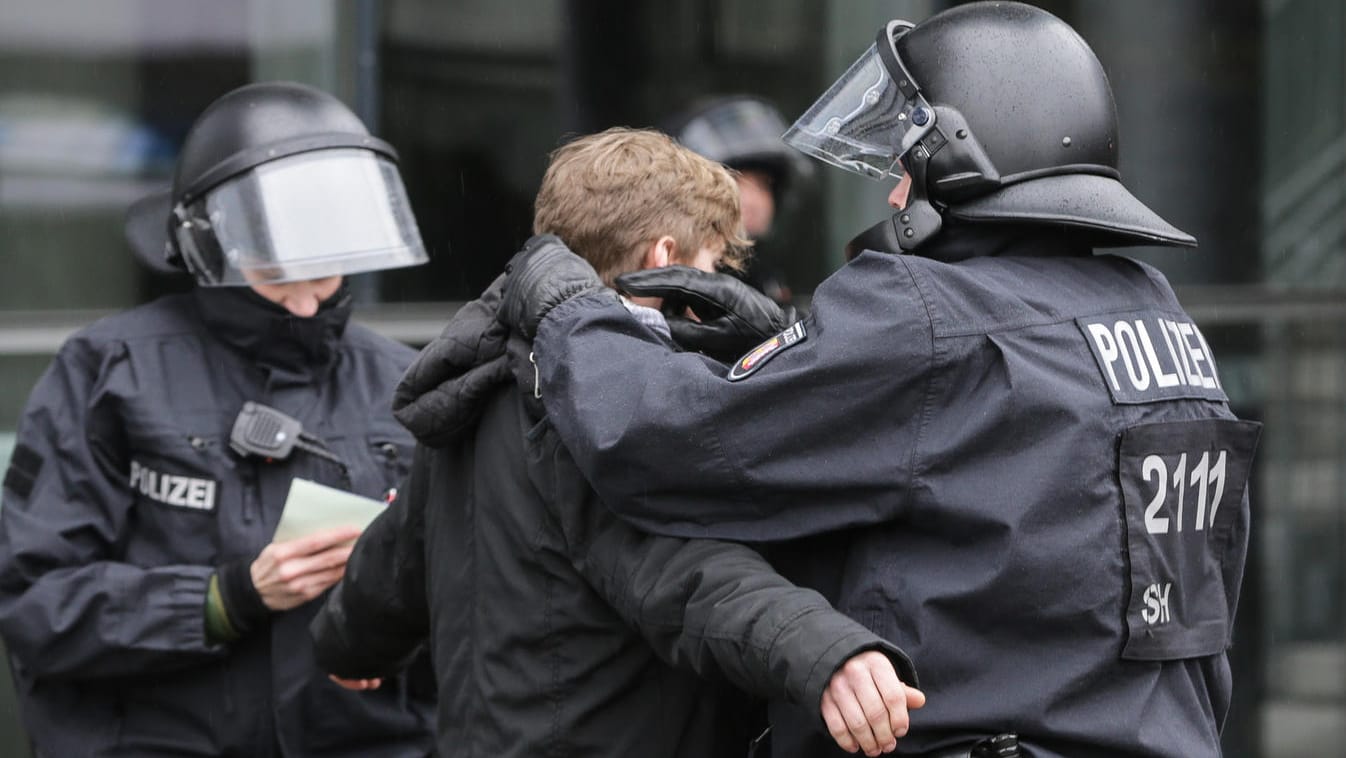 Ein Polizist durchsucht einen Demonstranten, der gegen den Landesparteitag der AfD in Kiel protestiert hat. Auch die Polizei in Köln rechnet mit Gewalt von linken Gruppierungen.