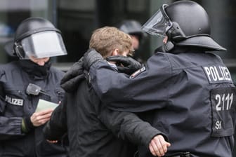 Ein Polizist durchsucht einen Demonstranten, der gegen den Landesparteitag der AfD in Kiel protestiert hat. Auch die Polizei in Köln rechnet mit Gewalt von linken Gruppierungen.
