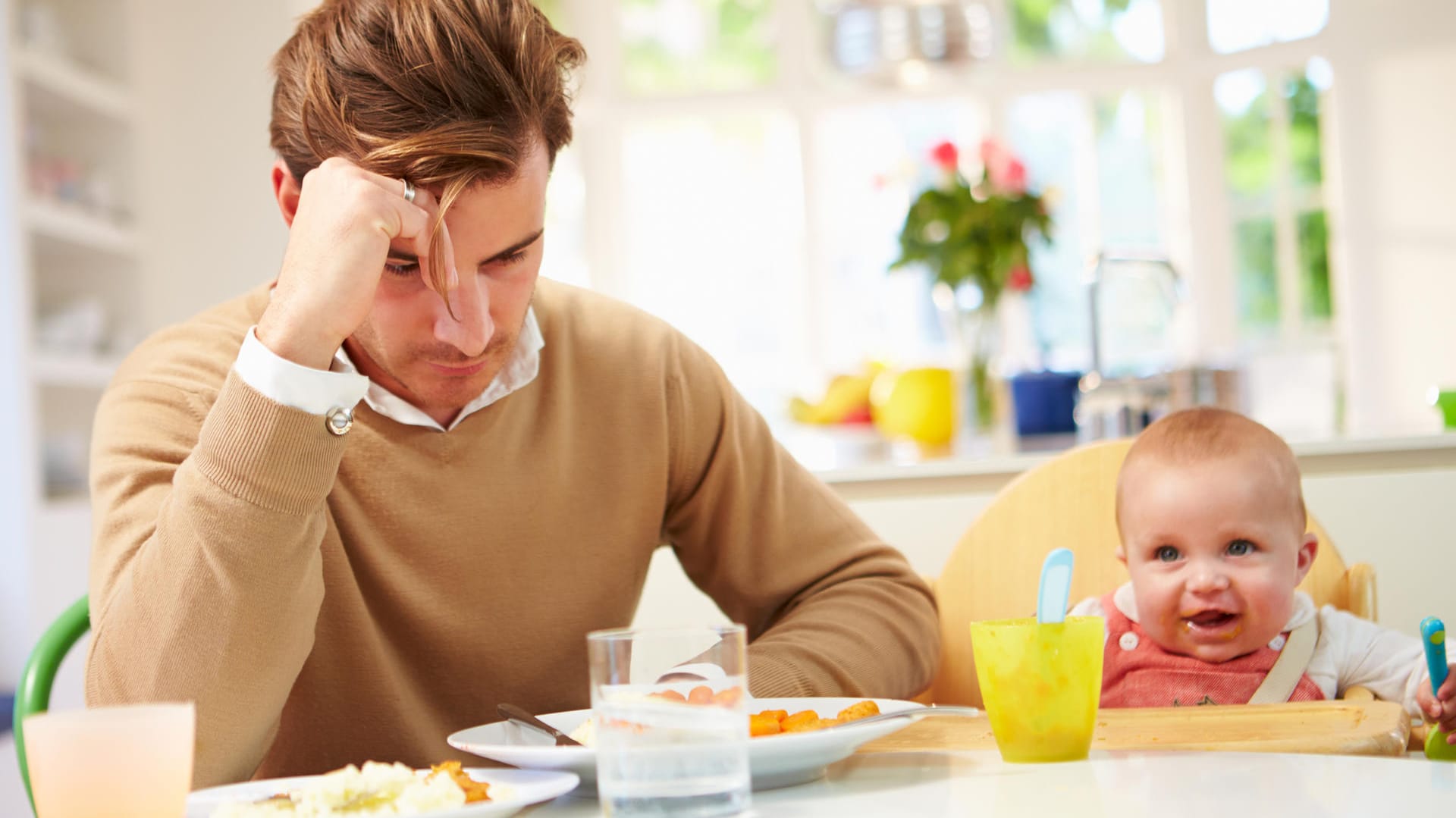 Ein Vater blickt unzufrieden auf den Küchentisch