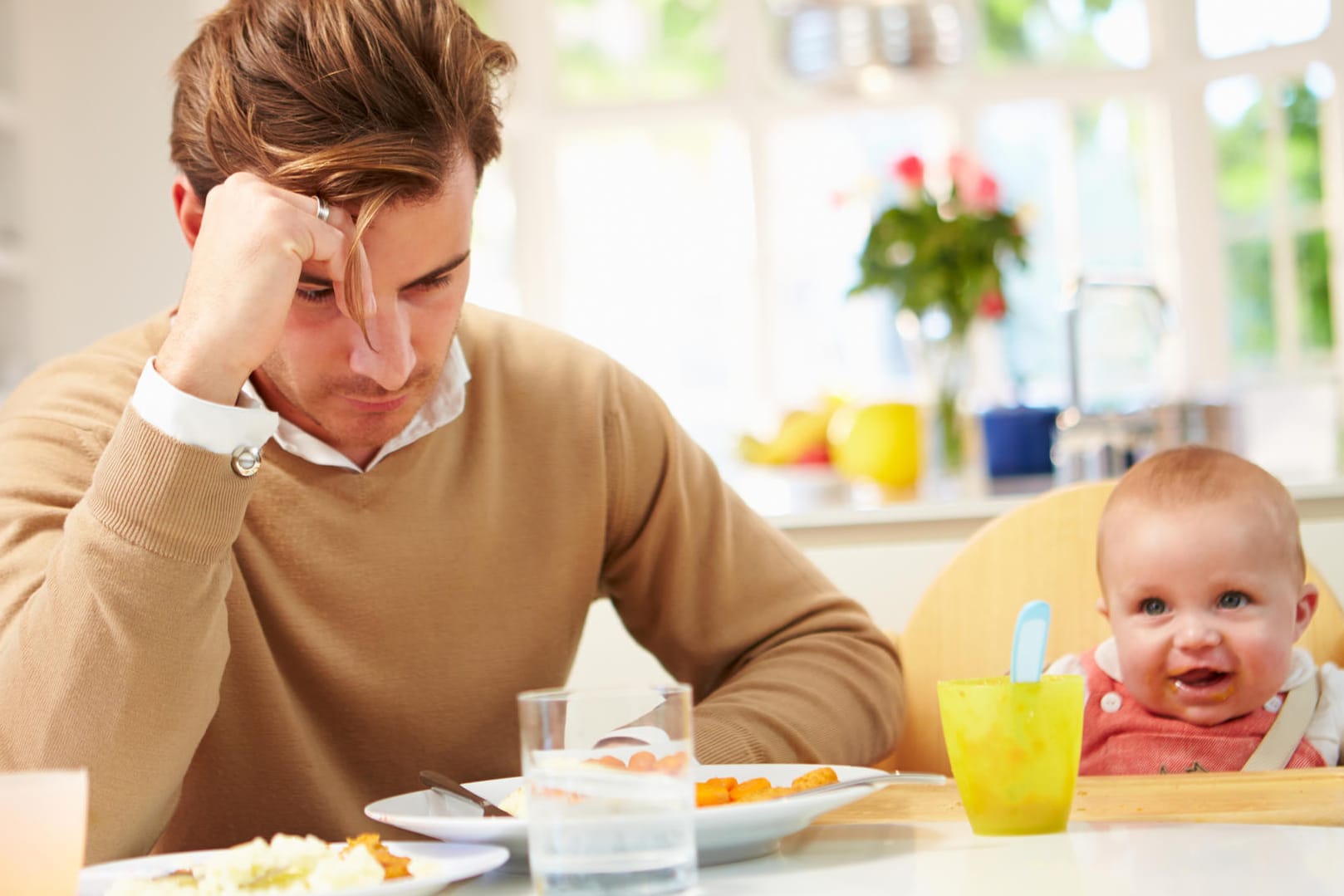 Ein Vater blickt unzufrieden auf den Küchentisch