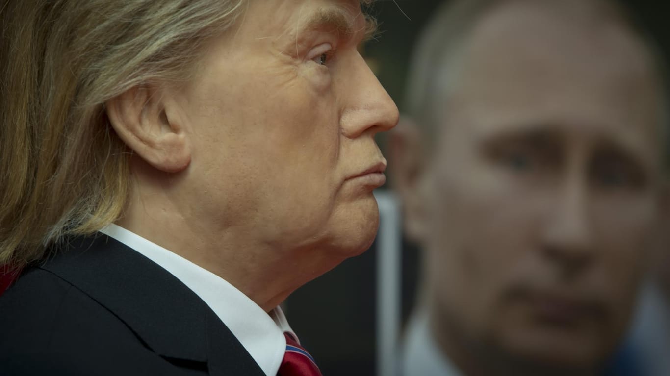 Eine Wachsfigur von Donald Trump vor einem Foto Putins.