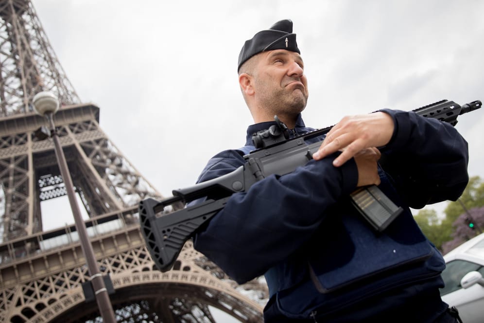 Ein schwer bewaffneter Polizist patroulliert am am Eiffelturm in Paris.