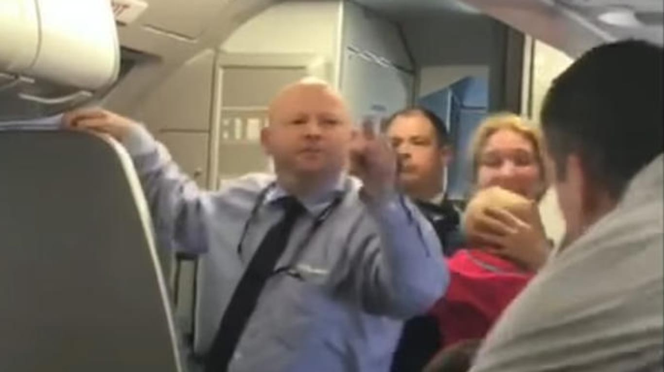 Der Steward bedroht einen der Passagiere, der sich für die weinende Frau einsetzte.