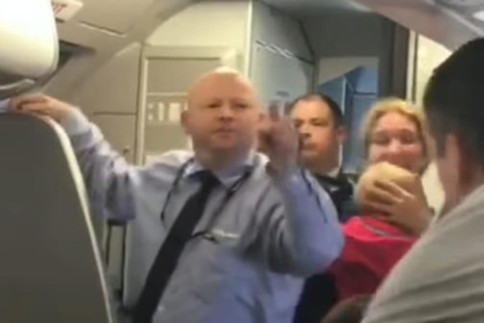 Der Steward bedroht einen der Passagiere, der sich für die weinende Frau einsetzte.