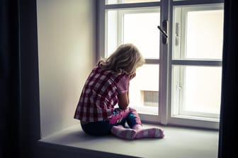 Ein Mädchen sitzt vor einem Fenster: Gewalt gegen Kinder lässt sich nicht auf Altersgruppen oder Schichten zurückführen.