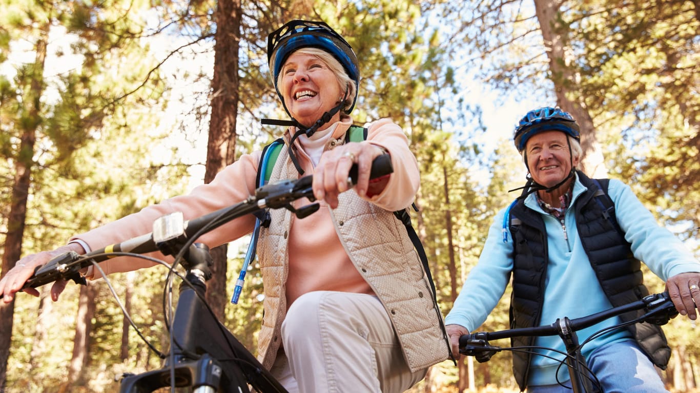 Ein aktives Rentner-Paar fährt Fahrrad im Wald.