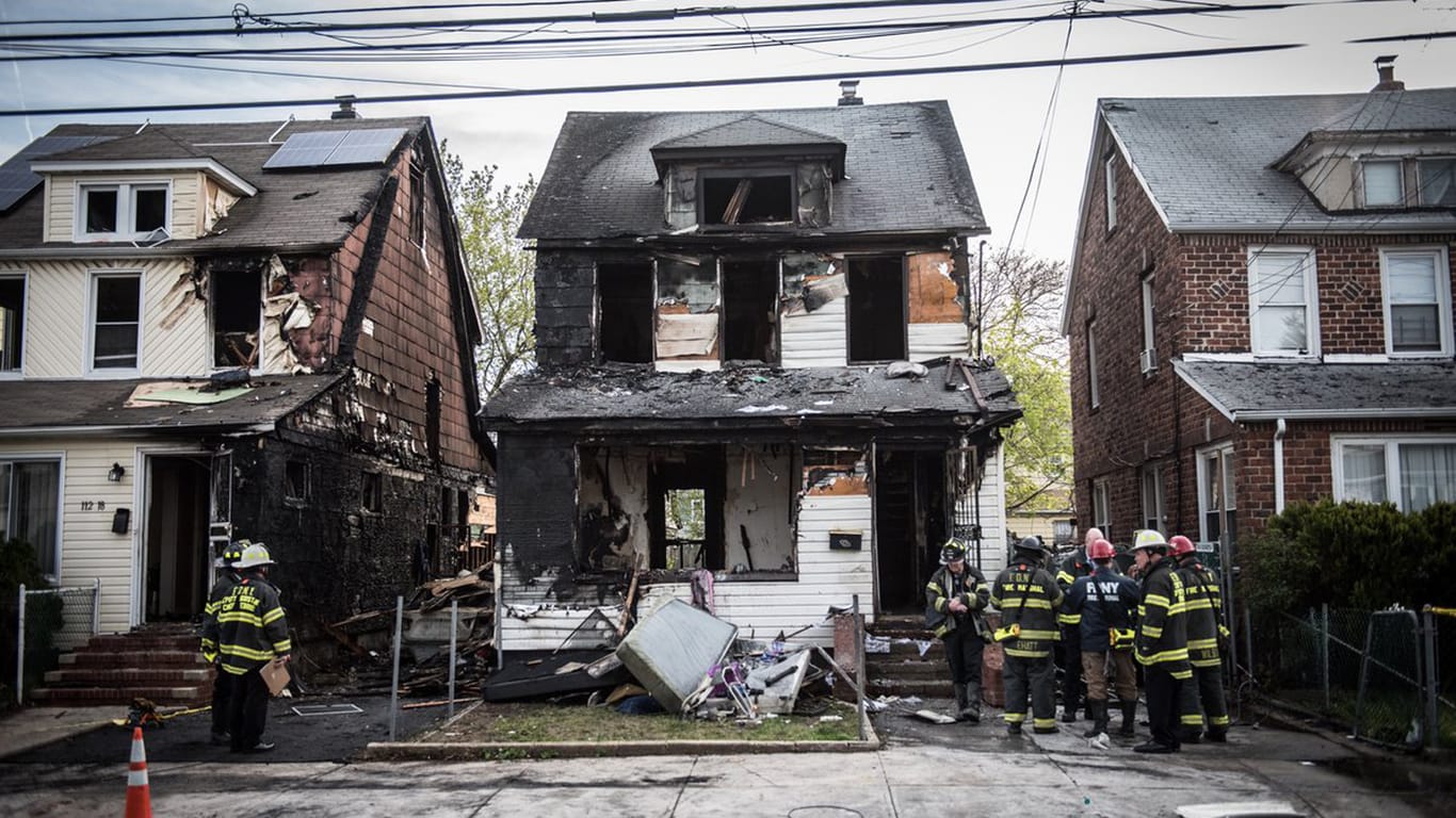 Die Männer der New Yorker Feuerwehr stehen vor dem abgebrannten Wohnhaus, in dem sich die Tragödie ereignet hat.