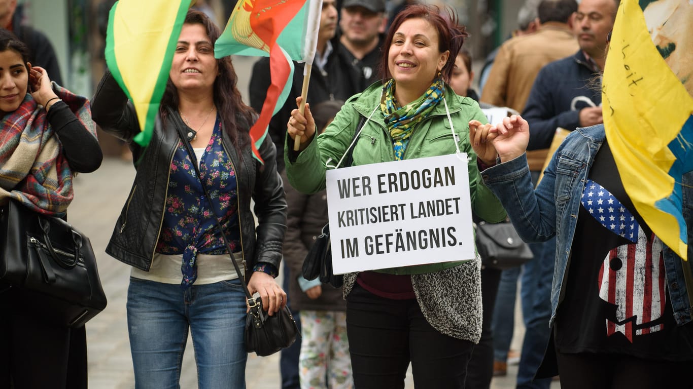 Mit einem Plakat "Wer Erdogan kritisiert landet im Gefängnis" und demonstriert eine Frau unter dem Motto "Gegen Krieg und Staatsterror, für Frieden in Kurdistan und ein friedliches Zusammenleben".