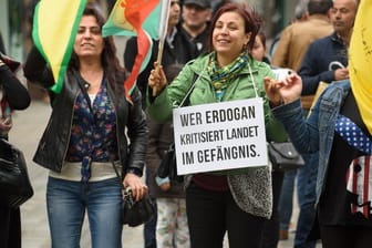 Mit einem Plakat "Wer Erdogan kritisiert landet im Gefängnis" und demonstriert eine Frau unter dem Motto "Gegen Krieg und Staatsterror, für Frieden in Kurdistan und ein friedliches Zusammenleben".