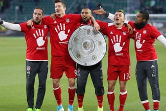 Die Spieler des FC Bayern feiern mit einer Meisterschale aus Pappe den fünften Titel in Serie.