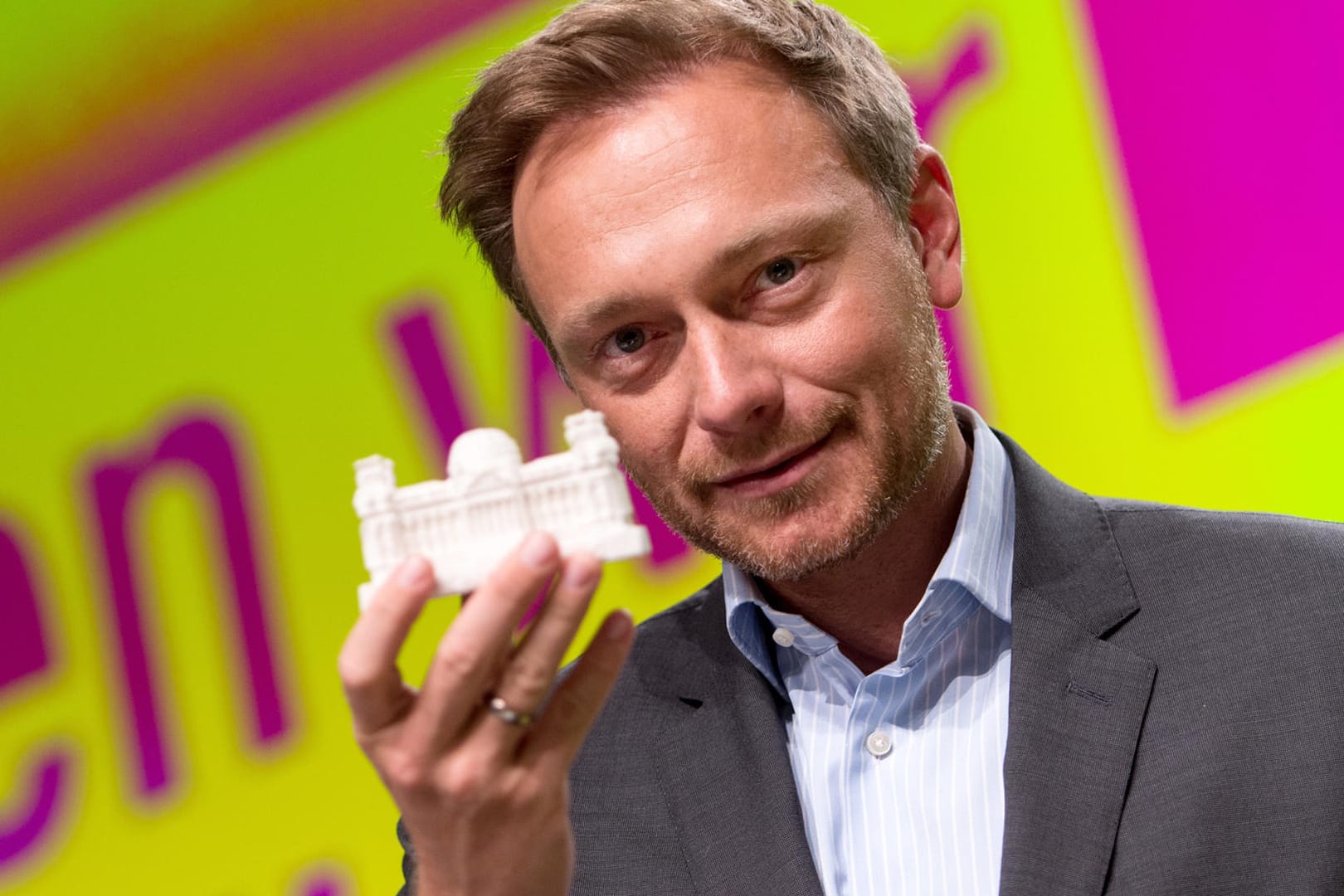 Der FDP-Vorsitzende Christian Lindner hält ein kleines Modell des Bundestags in der Hand.