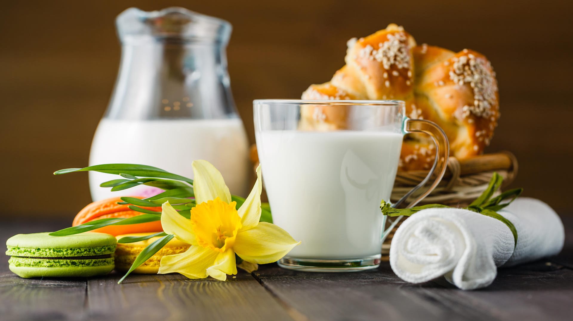 Ein Glas Milch steht vor einem Brotkorb.