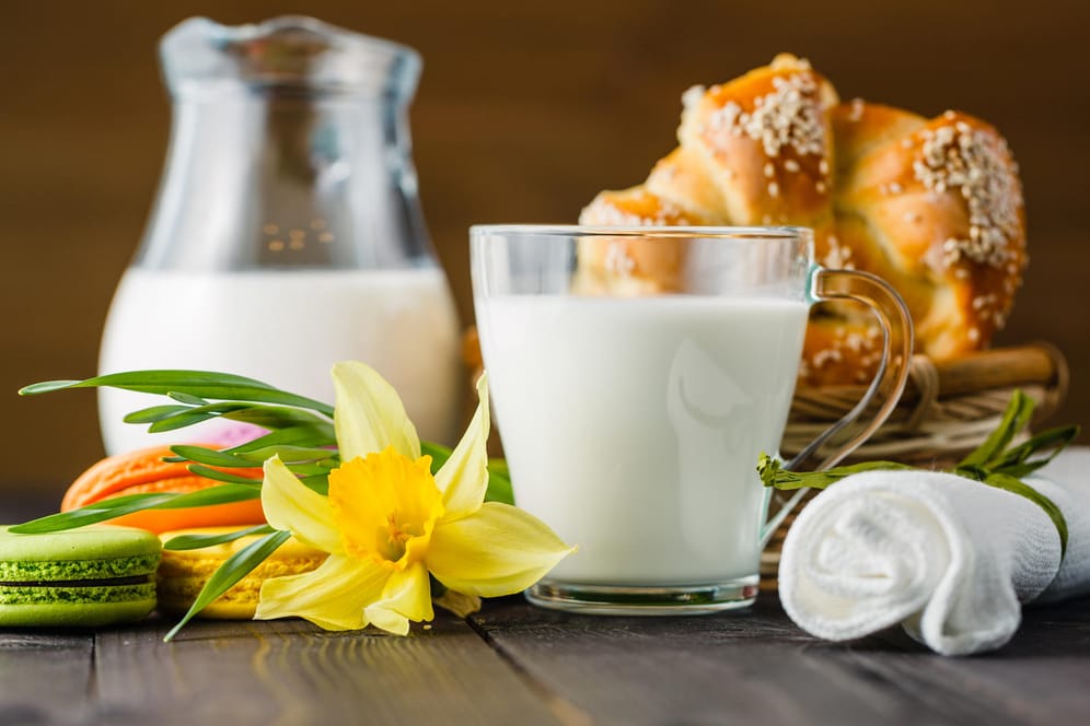 Ein Glas Milch steht vor einem Brotkorb.
