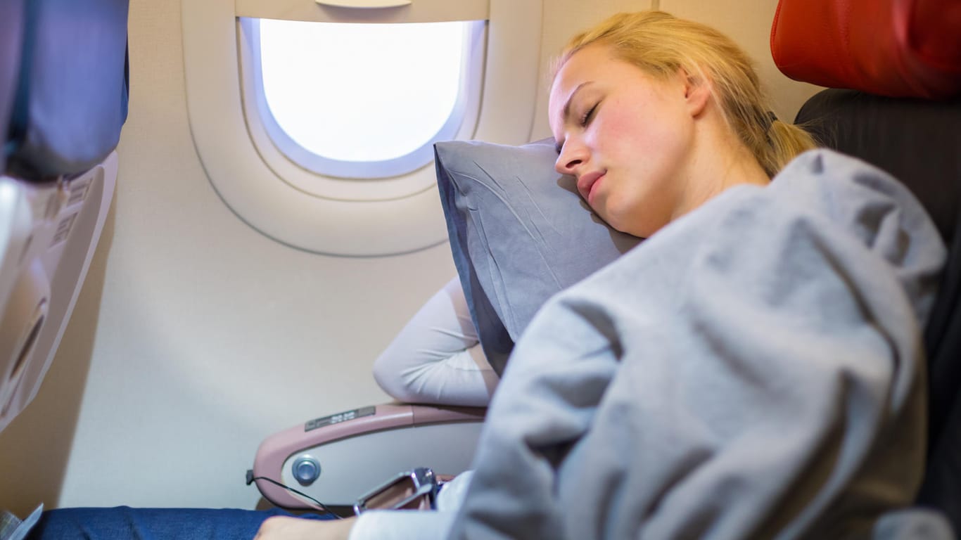 Eine Frau schläft im Flugzeug