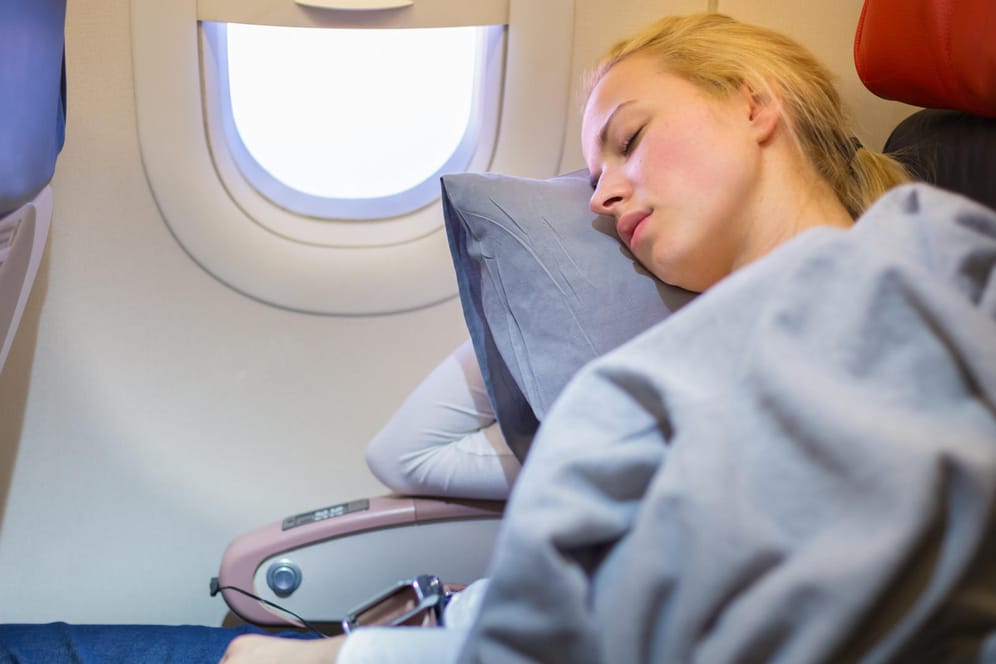 Eine Frau schläft im Flugzeug