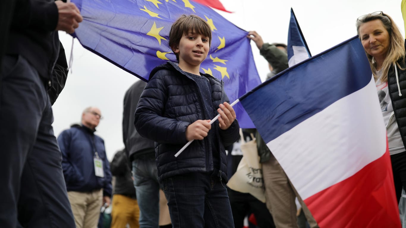 Ein Junge trägt am Louvre in Paris bei der Wahlparty der Macron-Anhänger eine französische Flagge.