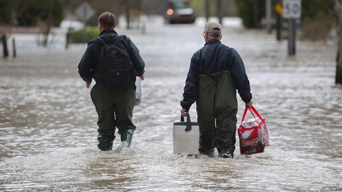 Zwei Männer überqueren eine überflutete Straße im Montreal.