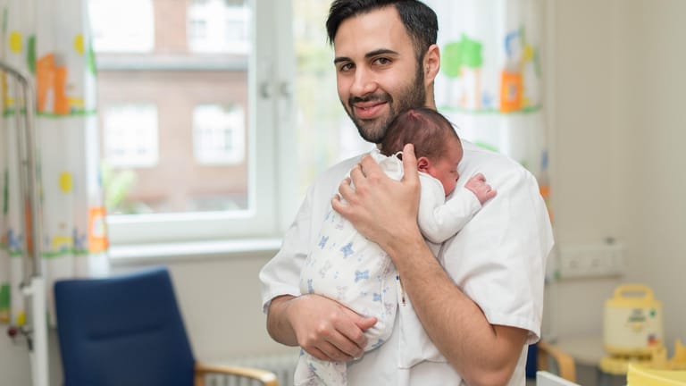 Entbindungshelfer Milco Messina hält ein neugeborenes Baby in seinen Armen.