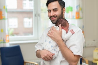 Entbindungshelfer Milco Messina hält ein neugeborenes Baby in seinen Armen.