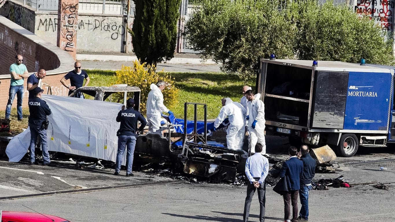Forensiker der Polizei untersuchen die Überreste des ausgebrannten Wohnwagens in Rom.