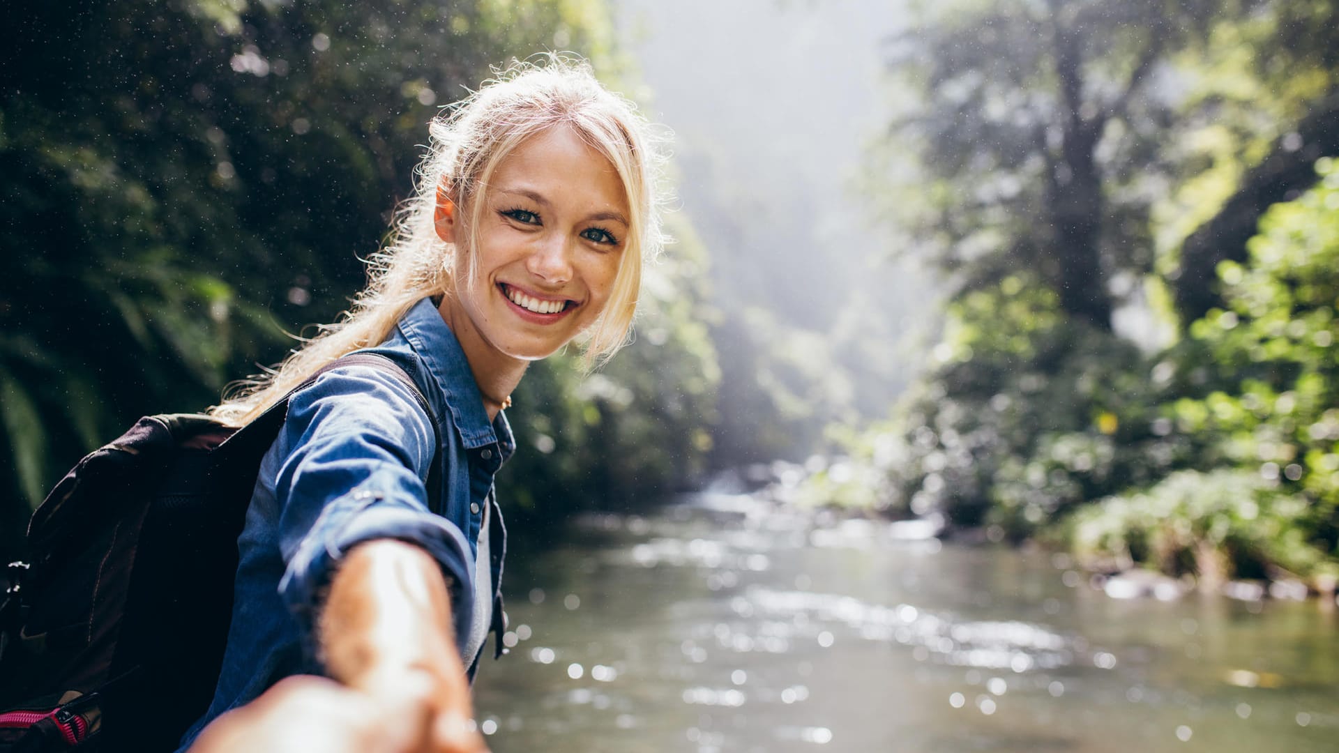 Wandererin hält die Hand ihres Partners am Fluss