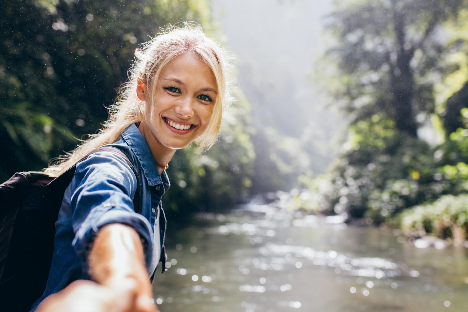 Wandererin hält die Hand ihres Partners am Fluss