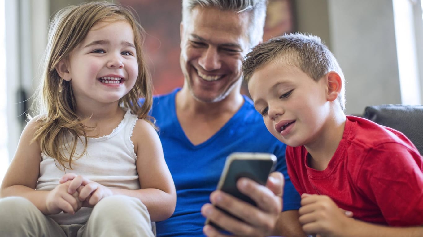 Vater zeigt Kindern Fotos auf dem iPhone 7