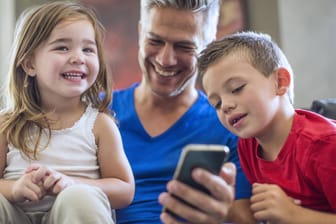 Vater zeigt Kindern Fotos auf dem iPhone 7
