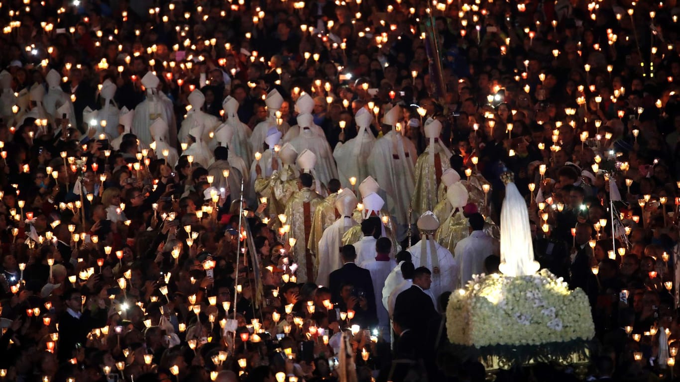 Die Marienstatue wird in Fatima (Portugal) durch die Menge der Pilger getragen, die nach Einbruch der Dunkelheit brennende Kerzen hochhielten.