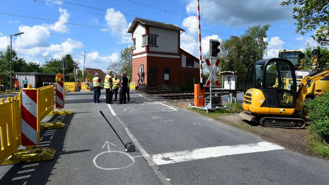Rettungskräfte stehen nach dem Zusammenstoß des LKW's mit dem Regionalzug in Eilvese (Niedersachsen) am Bahnübergang mit Behelfsschranken.