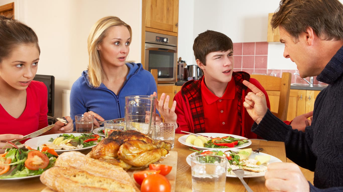Eine Familie mit zwei jugendlichen Kindern streitet am Essentisch