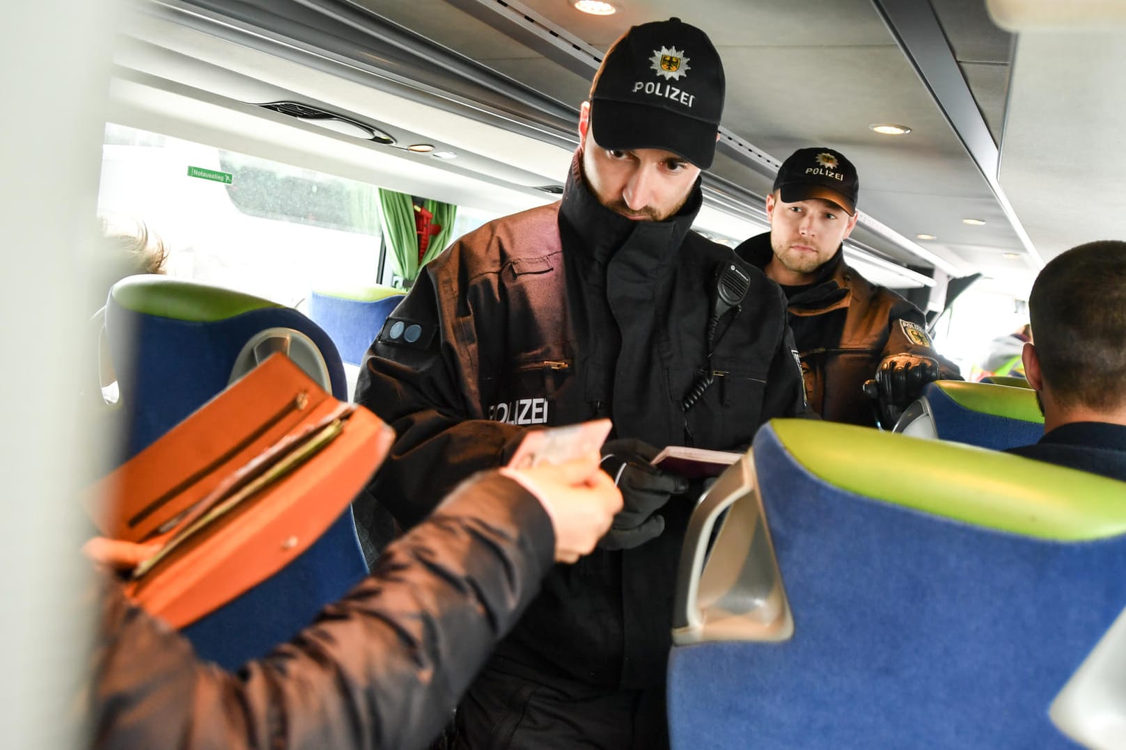 Polizisten kontrollieren die Fahrgäste eines Reisebusses.