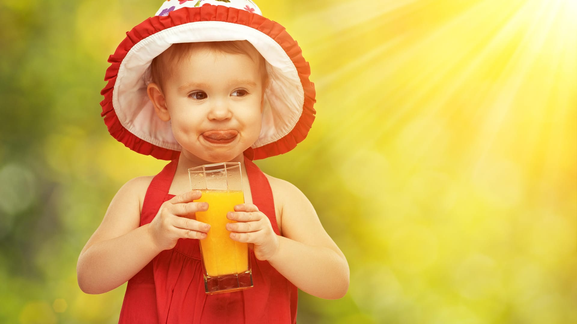 Ein kleines Mädchen trinkt ein Glas Orangensaft: Kinder trinken gerne Fruchtsäfte. Aber wie viele Gläser täglich sind in Ordnung?