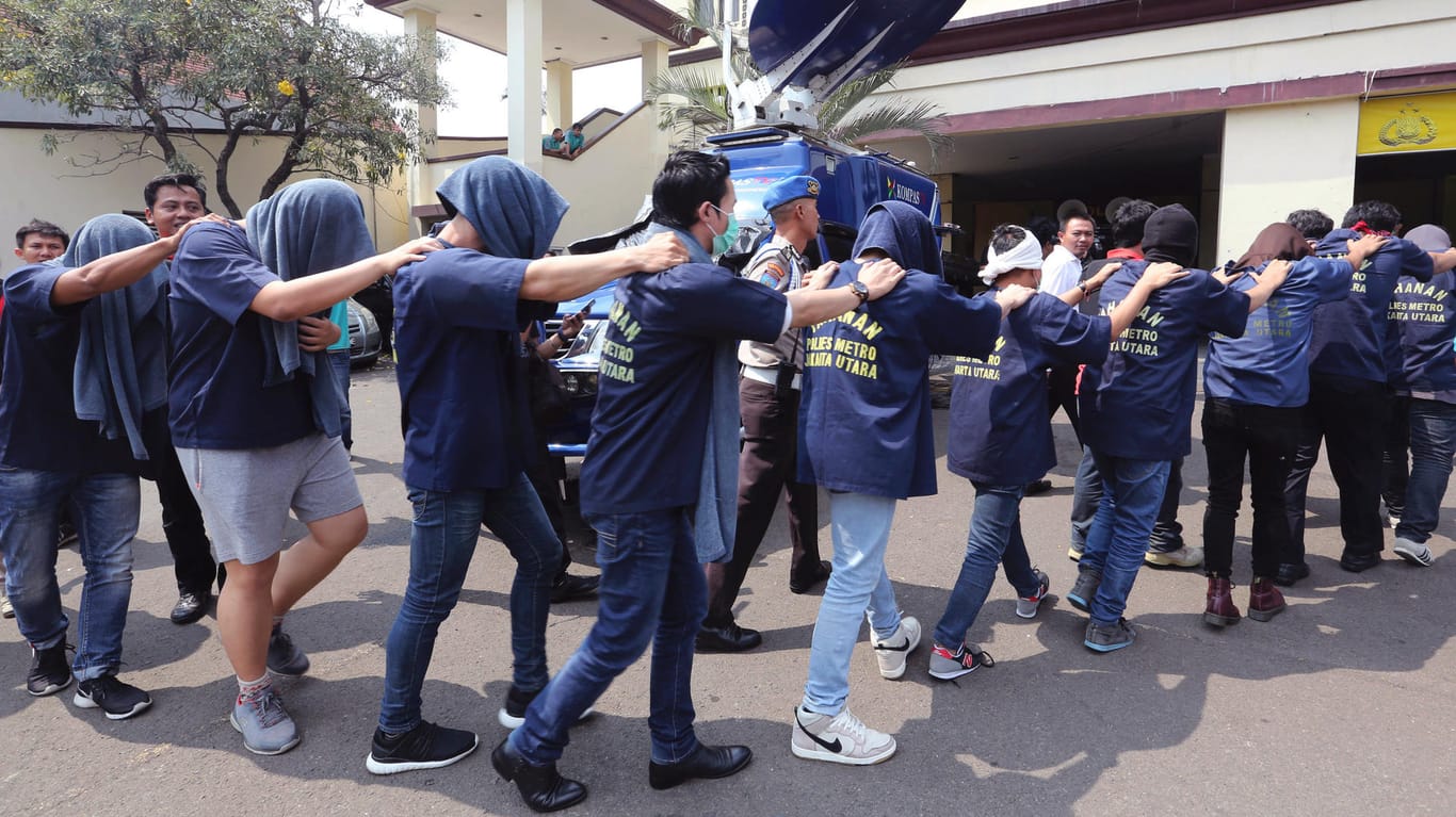 Polizisten in Jakarta führen die festgenommenen Männer aus dem Club.