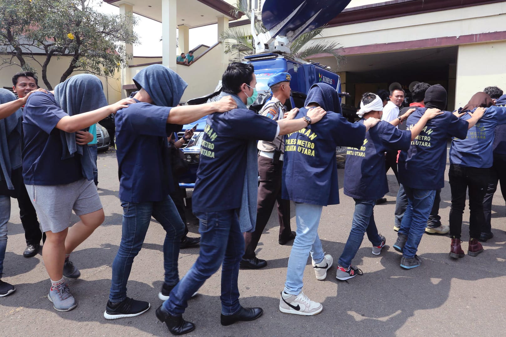 Polizisten in Jakarta führen die festgenommenen Männer aus dem Club.