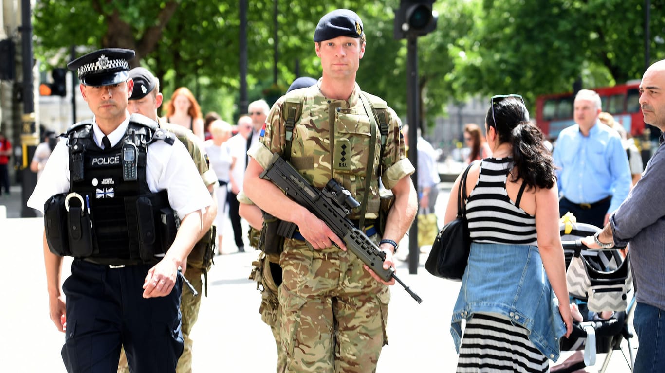 Ein bewaffneter Soldat und ein Polizist patrouillieren in Manchester.