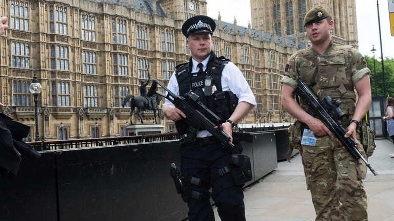 Ein bewaffneter Soldat und ein Polizist patrouillieren in London.