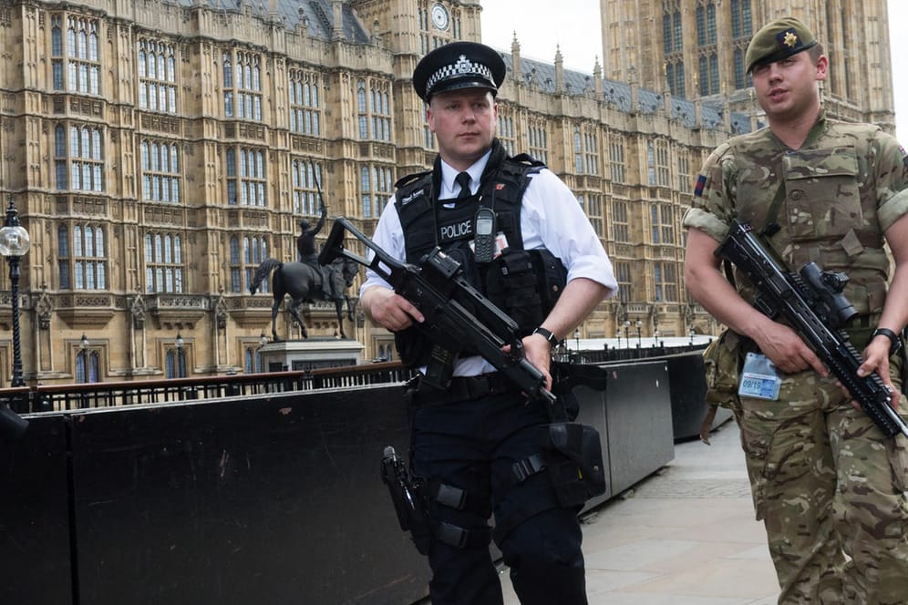 Ein bewaffneter Soldat und ein Polizist patrouillieren in London.