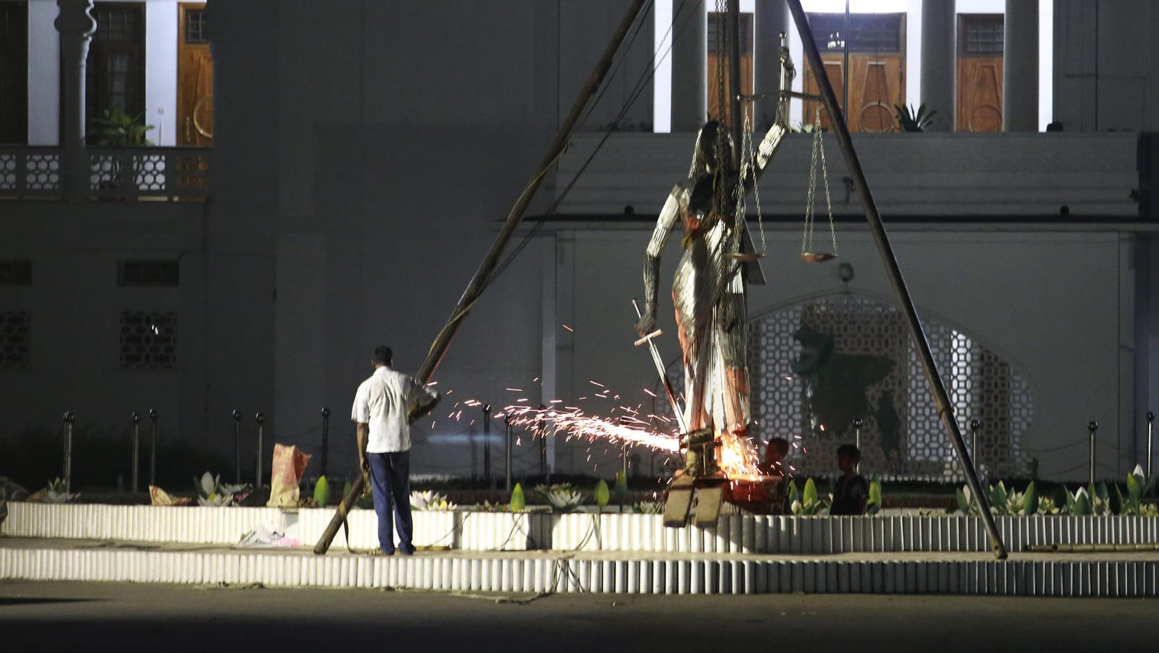 Arbeiter entfernen in Dhaka die Justitia-Statue vor dem obersten Gerichtshof. Arbeiter entfernen in Dhaka die Justitia-Statue vor dem obersten Gerichtshof.